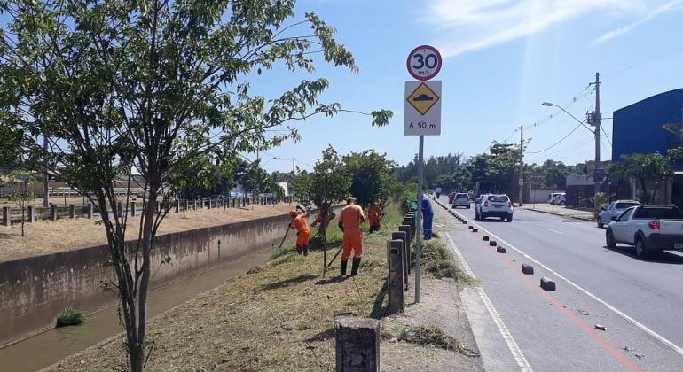 SLU executa os serviços de capina e roçada das margens, taludes e leitos dos córregos e das nascentes públicas. Foto: Osvaldo Machado/PBH Garis limpam beira de córrego durante o dia.