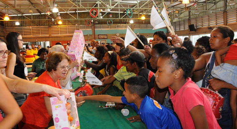Mulheres distribuem presentes doados para mais de 30 crianças em Restaurante Popular no dia de Natal.