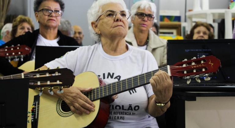 Cerca de dez idosos tocando violão