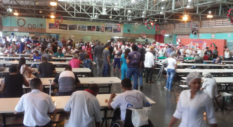 Quatro mil refeições no Almoço de Natal do Restaurante Popular serão servidas por cerca de cerca de 180 voluntários no dia 25/12. Foto: Divulgação PBH Mais de cem pessoas, umas sentadas e outras em pé, no almoço de Natal do Restaurante Popular.