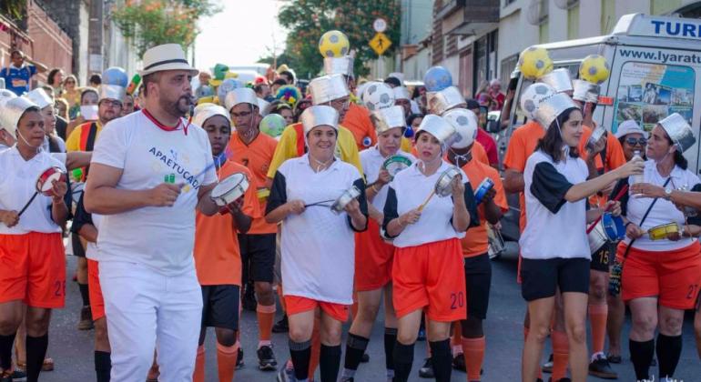 Bloco do carnaval da Apae, com integrantes fantasiados e tocando instrumentos musicais.
