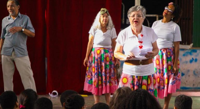 "EnvelheSER em BH" é destinado à população idosa e tem atrações culturais gratuitas a partir das 13h no Centro de Referência da População Idosa. Foto: Stênio Lima/PBH Três senhoras com camisetas brancas e saias de chita se apresentam.