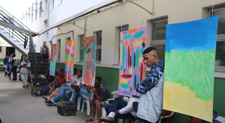 O Centro Especializado para População em Situação de Rua completa cinco anos em junho e contabiliza 8.500 atendimentos por mês. Foto: Stenio Lima/PBH Homens e mulheres ao lado de painéis coloridos no aniversário do Centro Especializado para População em Situação de Rua.