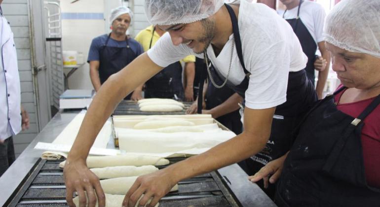 Rapaz com touca faz pães. 