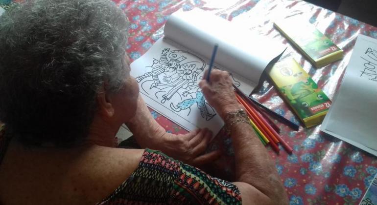 Movimento Gentileza leva entretenimento a idosos durante o período de quarentena Idosa colorindo um livro de colorir