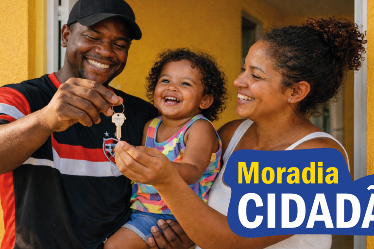 Uma família composta por um homem, uma mulher e uma criança aparecem sorridentes em uma foto gerada por inteligência artificial. Há o texto Moradia Cidadã.