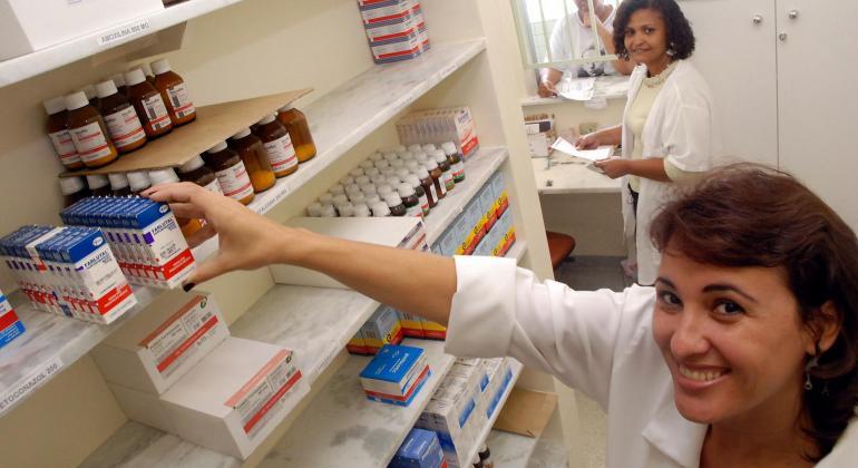 Secretaria Municipal de Saúde desenvolve ações para incentivar o uso consciente de antibióticos. Foto: Divulgação PBH Atendente no posto de saúde pega remédio tarja vermelha na prateleira; foto ilustrativa.