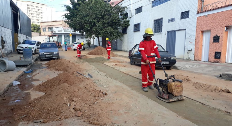 Três homens pavimentam a rua nova Friburgo, durante o dia. 