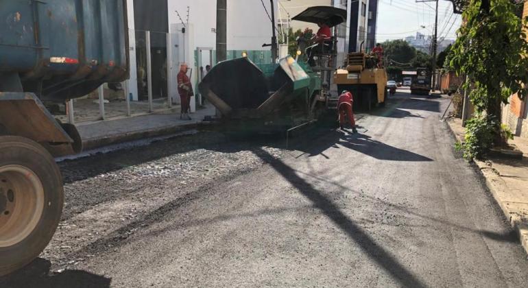 Rua sendo recapeada com máquinas e homens trabalhando