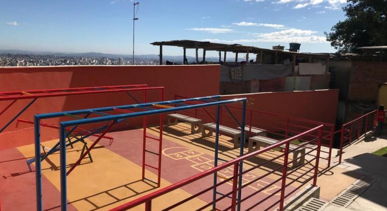 Obras no Aglomerado da Serra eram aguardadas desde 2011 e contemplaram três becos da Vila Aparecida. Foto: Divulgação PBH Espaço multicolorido com jogo de amarelinha pintado no chão e outros brinquedos infantis, durante o dia.