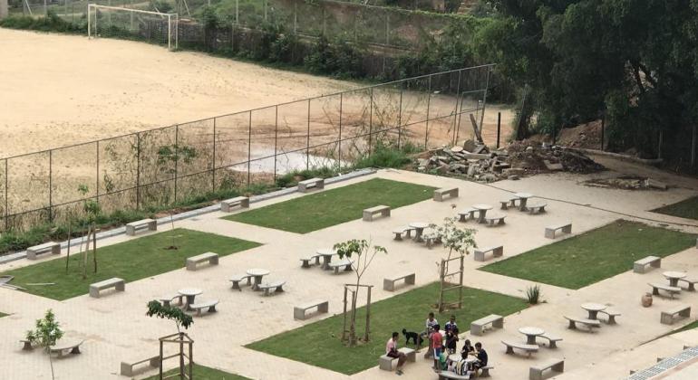 Sete adolescentes ao redor de uma das dez mesas do complexo esportivo Vila Olímpica, no Morro das Pedras, ao lado de quadra. 