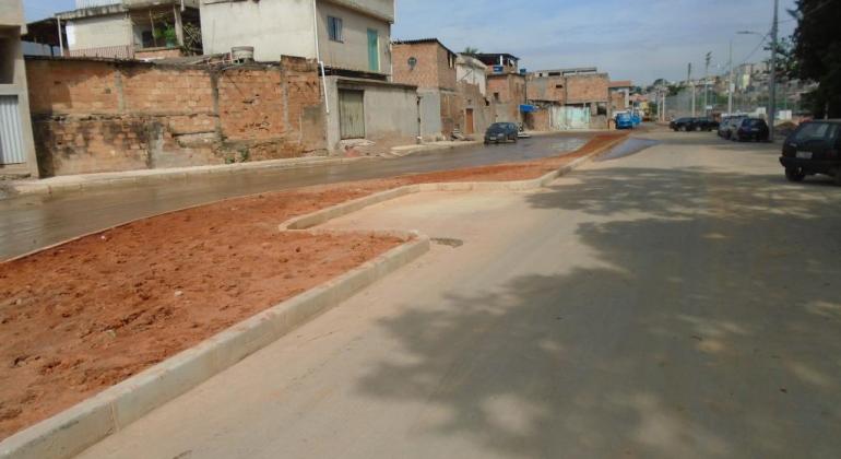 Rua asfaltada, com casas à esquerda. 