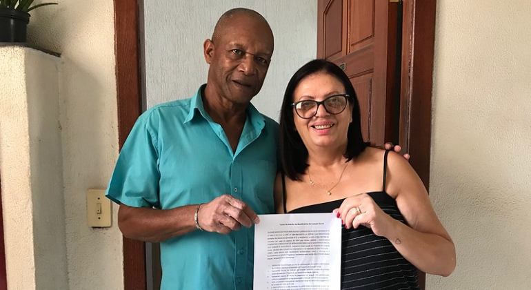 A primeira família assinou o contrato de aluguel no dia 14/11 na Urbel; etapa do projeto contempla 202 idosos. Foto: Divulgação PBH Casal segura papel digitado à mão.
