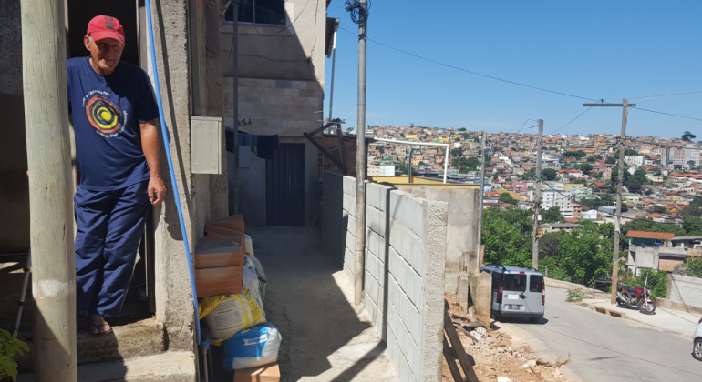 A implantação da rua 24 de Agosto/Diamante, no Aglomerado Morro das Pedras, região Oeste de BH, tem previsão de entrega em junho de 2019. Foto: Divulgação PBH Homem de boné vermelho e camiseta azul, ao lado de rua com obras de urbanização, durante o dia.