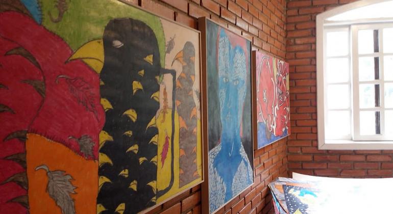 Exposição Universo Personas marca aniversário do Centro de Convivência Venda Nova. Foto: Janete Ribeiro Três quadros coloridos expostos na parede de uma sala.