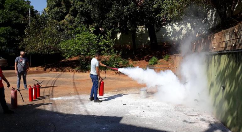 Na Regional Venda Nova, servidores participam de treinamento de prevenção e combate a incêndio. Foto: Divulgação PBH Homem, em terreno vago a céu aberto, usa extintor de incêndio.