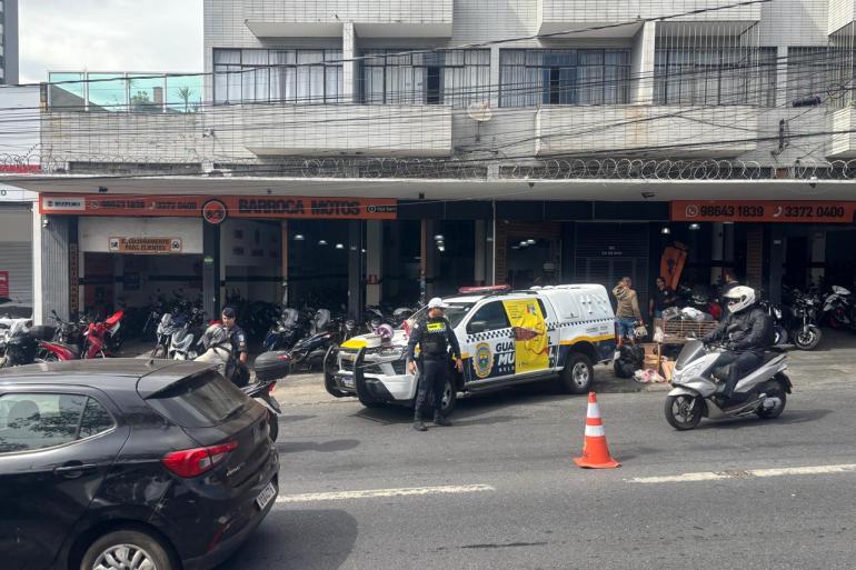 Guarda Municipal encerra Semana Nacional do Trânsito com blitz educativa para motociclistas Uma viatura da Guarda Municipal de Belo Horizonte encontra-se estacionada em frente a um estabelecimento comercial, com agentes ao redor e materiais da blitz educativa posicionados na viatura. A circulação do trânsito no local é orientada por cones de sinalização, enquanto carros e motocicletas transitam ao redor.