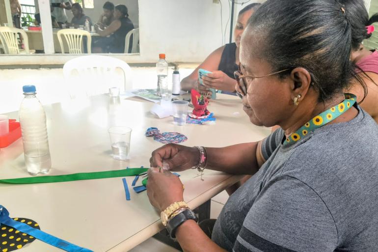 Projeto “Respeita a Minha História” oferece espaço de diálogo com foco em fortalecimento e autonomia das mulheres no Barreiro Mulheres participam de oficina de fuxico, ao redeor de uma mesa clara.