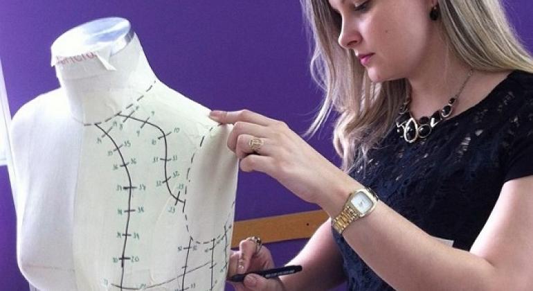 Museu da Moda promove aulas abertas de moda e design Costureira e modelista faz anotações com caneta preta em manequim branco. Foto: Feu Cangussu