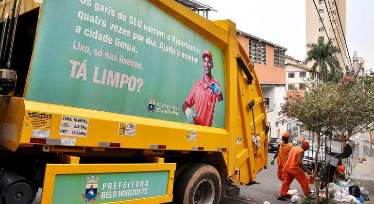 Garis da SLU recolhem lixo em rua da bairro, seguidos por caminhão de lixo, durante o dia. Foto: SLU