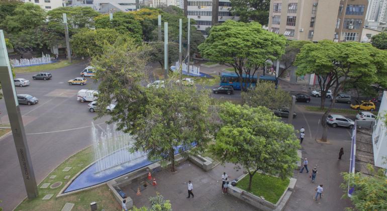 Praça Diogo Vasconcelos (Savassi) vista de cima, nela pessoas estão caminhando. A fonte de água está ligada e tem muitas árvores.