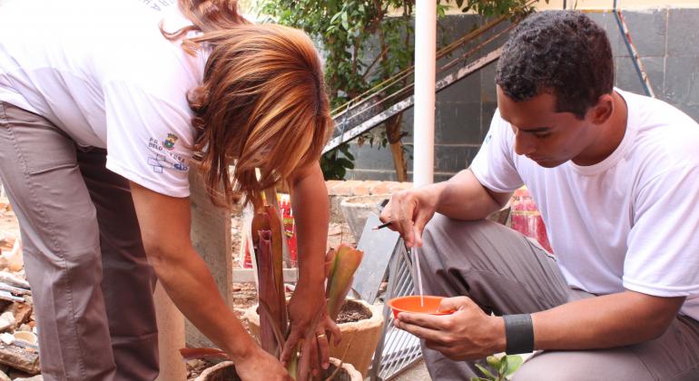Agentes comunitários de saúde veificam água verificam plantas em vasos e pratinhos durante o dia. Foto: Márcio Martins
