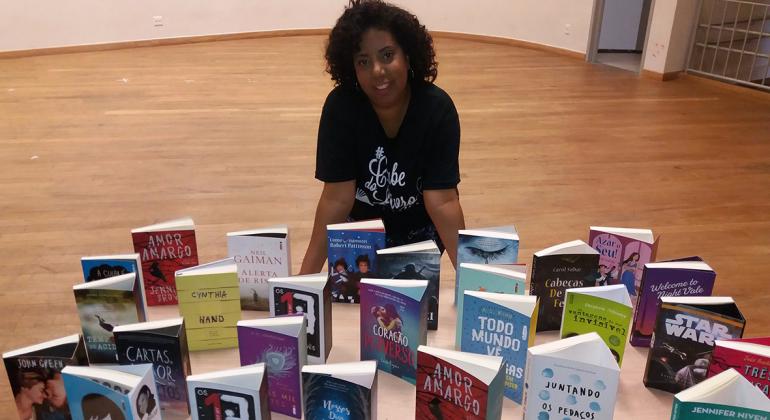 Escritora assentada com vários livros à frente. Foto: Divulgação