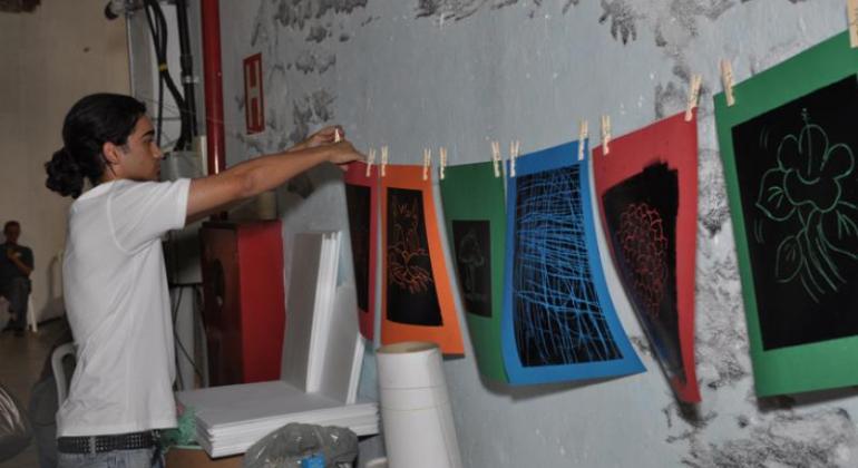Trabalho de portador de sofrimento mental. Portador de sofrimento mental pendura trabalhos de fundo com cores diversas com centro preto em varal.