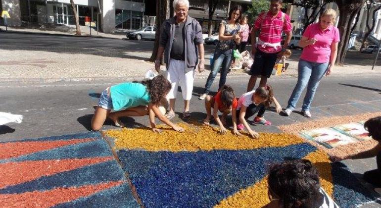 Celebração de Corpus Christi - Foto: Arquivo Igreja da Boa Viagem Crianças, adultos e idosos no chão e de pé confeccionando tapetes de serragem