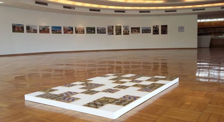 Vão principal da Casa do Baile com fotos de engenhos paraibanos ao fundo e ladrinlhos do mesmo local à frente. 