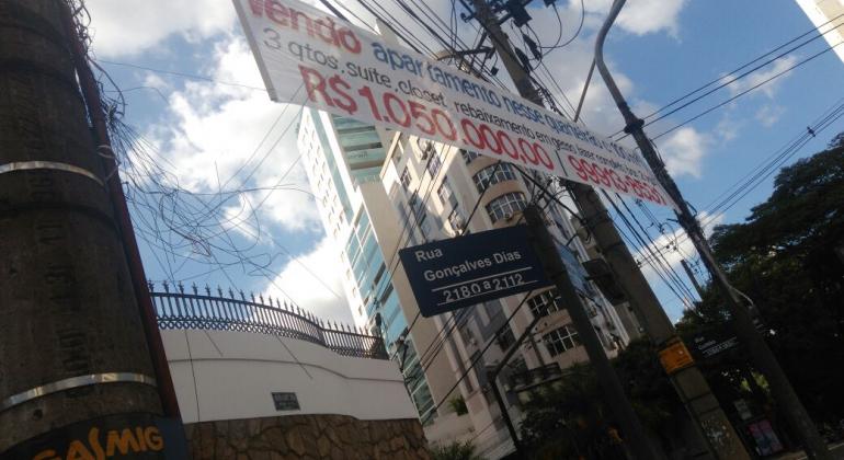 Retirada de faixas e banners na região Centro-Sul Placa informando Rua Gonçalves Dias 2180 a 2112, poste de energia á esquerda e faixa branca com dizeres de venda fixada de um poste a outro lado da rua