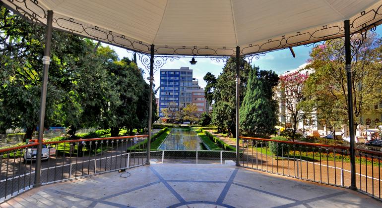 Arte e Loucura no Circuito Liberdade até 9 de julho - Foto: Divino Advincula/PBH Foto de dentro do coreto da praça da liberdade. A fonte de água, que fica à frente do coreto, está parada. Ao fundo, prédios do entorno da praça da Liberdade.