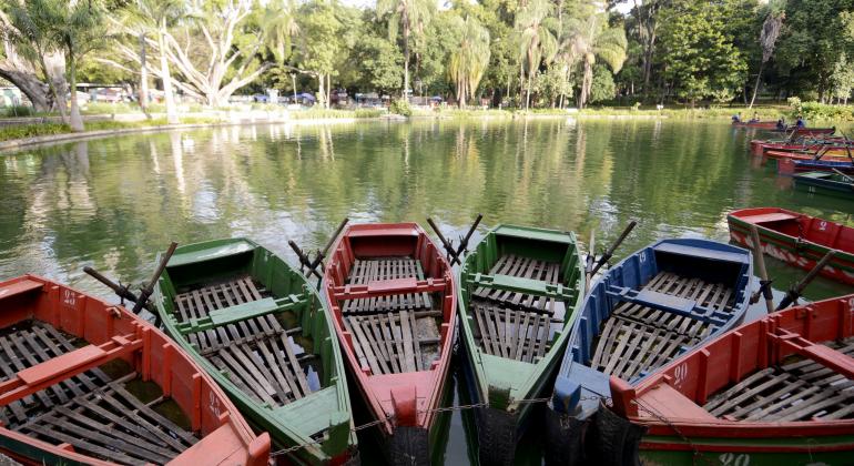 Lago do parque municipal. No primeiro plano, barquinhos no cais. Ao fundo, árvores.