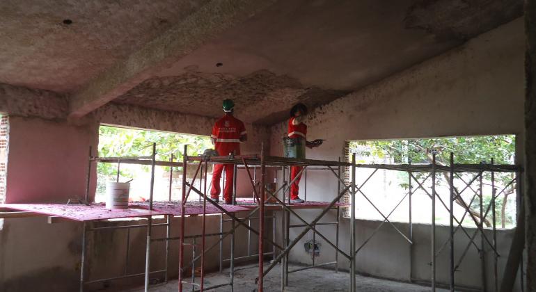 Dois servidores da construção civil trabalham em cima de cavaletes na ampliação do Centro de Referência da Pessoa Idosa