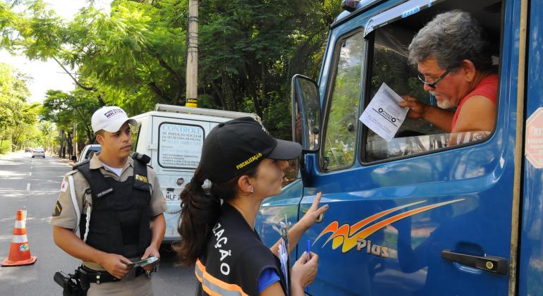 Fiscal da Prefeitura de Belo Horizonte e policiam militar conversam com motorista de caminhão em blitz da Operação Oxigênio