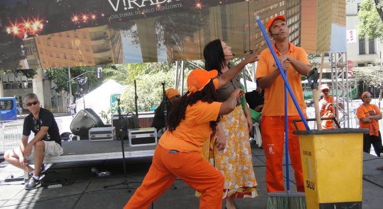 Grupo de teatro da SLU se apresenta. Atores estão vestidos de gari.