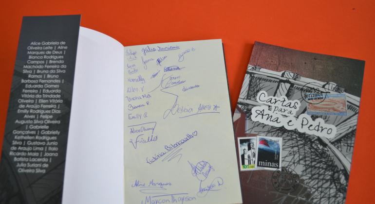BH em Pauta: Cartas de Ana para Pedro - Foto: Lidiane SantAna/PBH Livros. Um aberto e um fechado. No livro aberto, as assinaturas dos alunos que escreveram cartas.