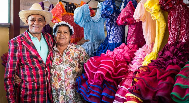 Casal Flora e Luiz, quadrilheiros, posam ao lado de vestidos juninos