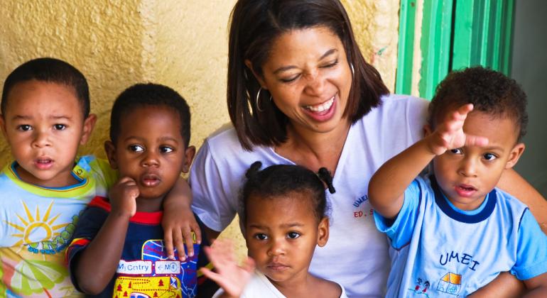 Prefeitura amplia número de vagas na Educação Infantil - Foto: Divino Advincula Quatro crianças de 3 anos acenam para a câmera. Professora está sorrindo.