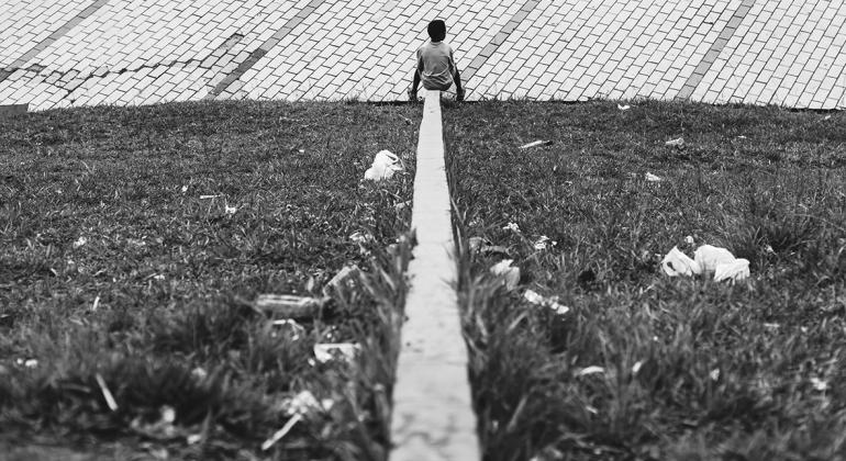 Foto que compõe a Exposição "A Cidade e o Ócio". Foto dividida ao meio horizontalmente por um "fio" de cimento, que leva a uma criança.
