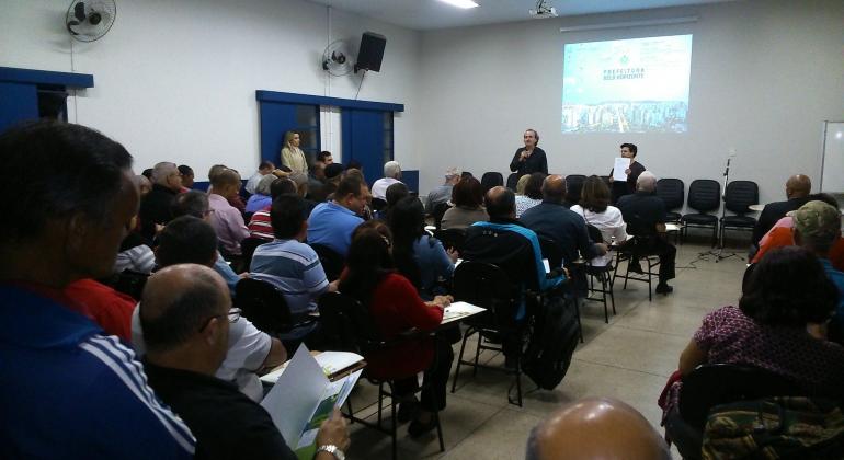 Projetos pilotos na Regional Nordeste buscam parcerias com entidades comunitárias estruturadas para fortalecer o poder público. Foto: Mara Damasceno Dois palestrantes em auditório da Regional Nordeste com mais de 20 pessoas falam sobre parcerias com entidades comunitárias.