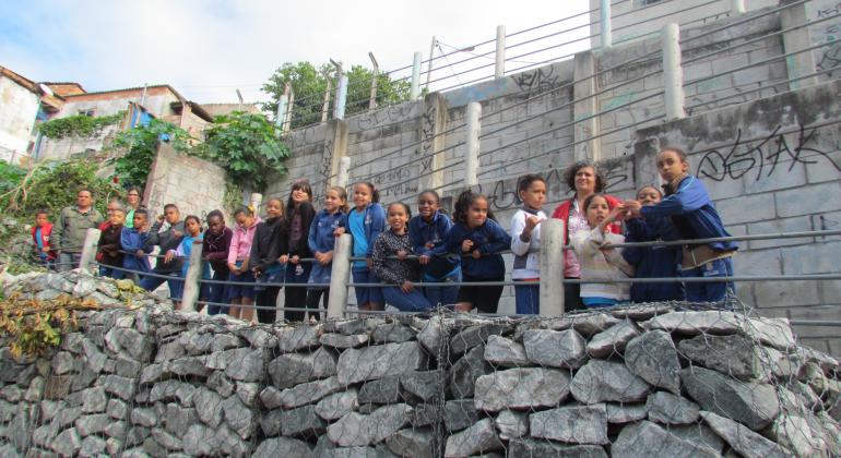 Grupo de crianças em frente a muro de pedras