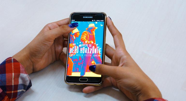 Prefeitura lança aplicativo do Arraial de Belo Horizonte - Foto: Divulgação Prodabel/Belotur Uma pessoa usa o celular. Na foto, mãos e a tela do celular com a página do aplicativo.