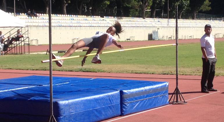 Estudante e atleta feminina pratica salto olímpico durante o dia