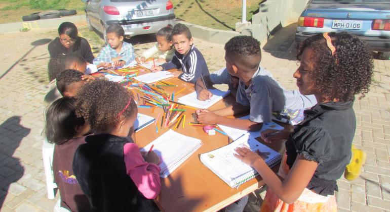 Atividades de desenho, pintura, música e artesanato, além de biblioteca, estimulam crianças e jovens de moradia popular na Pampulha. Foto: Urbel/PBH Oito crianças participam de oficina de artesanato no estacionamento Residencial Várzea da Palma, na Pampulha.