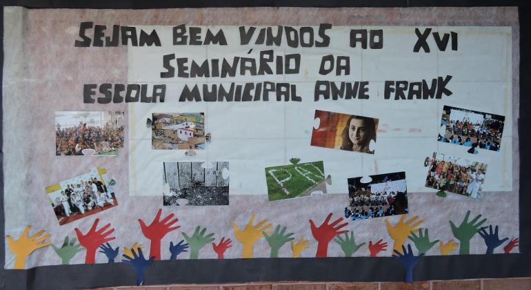 Painel de boas vindas ao XVI Seminario Socioambiental da Escola Municipal Anne Frankcom os dizeres: Sejam Bem-Vindos ao XVI Seminário da Escola Muncipal Anne Frank