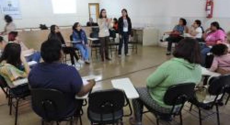 Encontro de Famílias atendidas pelos serviços socioassistenciais na Pampulha se reuniram para discutir a questão do trabalho infantil. Foto: Andréa Moreira/PBH Treze pessoas reunidas, sentadas em círculo, para as atividades do Encontro das Famílias.