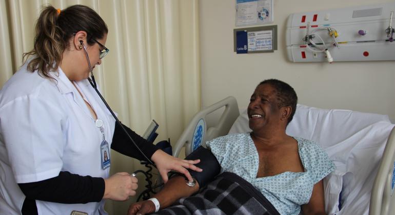 Após infarto, taxista é um dos primeiros beneficiados pela ampliação de leitos hospitalares em BH e elogia "tratamento VIP". Foto: Olavo Maneira/PBH O taxista Antônio Eustáquio é atendido por membro da equipe do Hospital Metropolitano Célio de Castro após infartp.