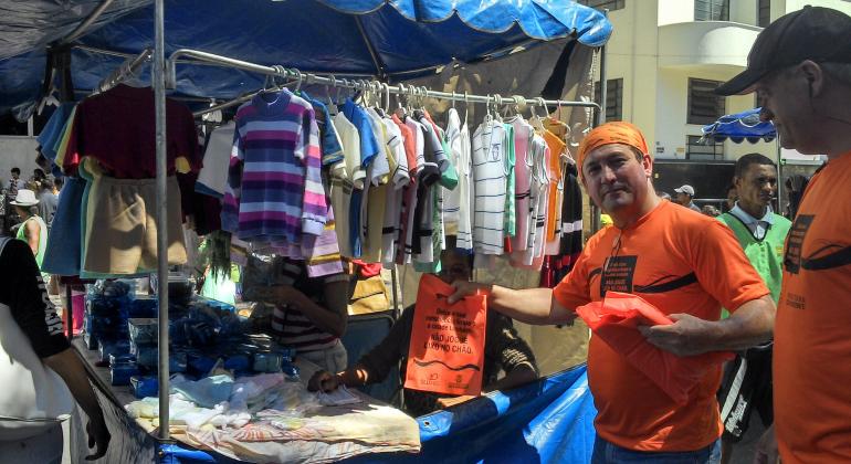 Membro da campanha de conscientização para limpeza com blusa, lenço e saquinho com mensagens educativas. 