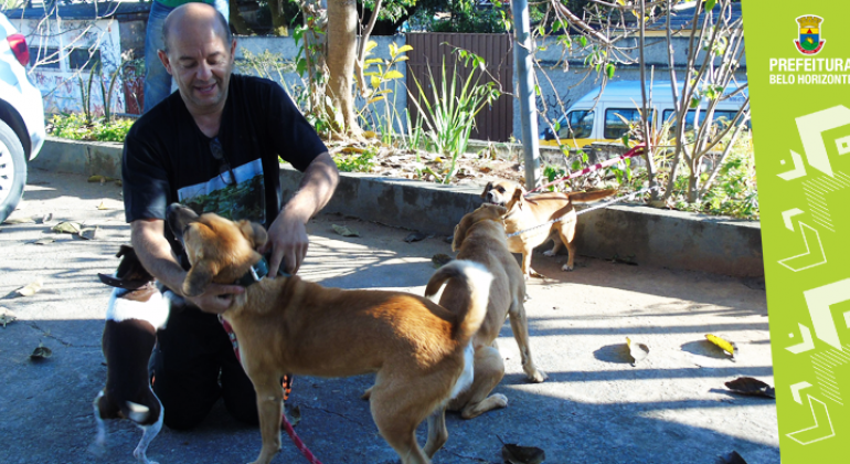Três cães e seu dono. Os cães utilizam serviços veterinários oferecidos pela Prefeitura.